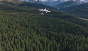 VTOL fixed-wing drone flying over a forest valley on battery power